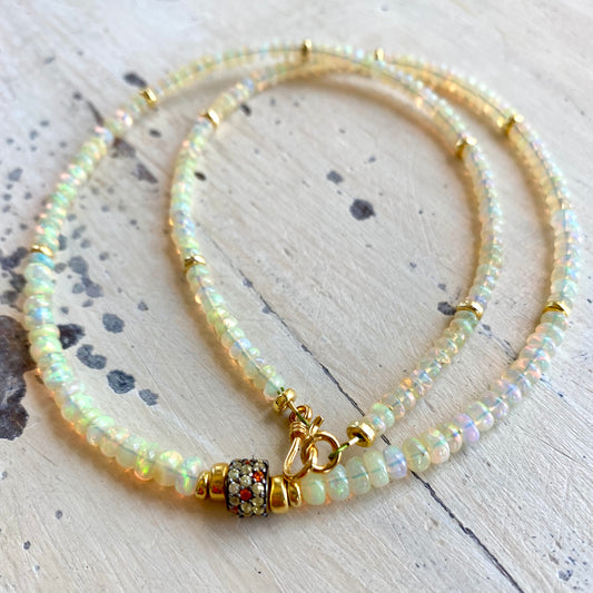 Ethiopian opal necklace flat lay, hand-knotted opal rondelles with sapphire pavé accent bead