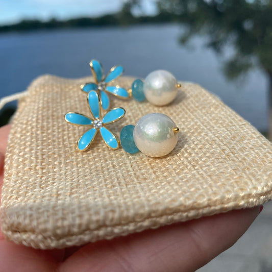 Edison Pearl Aquamarine Earrings featuring blue enamel flower design and lustrous pearls on a textured pouch.