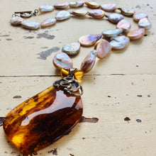 Lade das Bild in den Galerie-Viewer, Keshi pearl necklace with amber pendant displayed on white wooden table, close-up view.