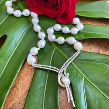 Cargar imagen en el visor de la galería, Handheld close-up of baroque pearl necklace on green leaf background, bridal jewelry detail.