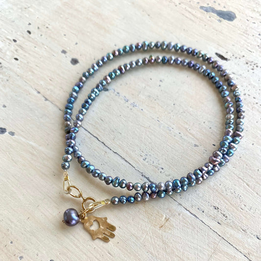 Black pearl hamsa necklace laid flat with mini rice pearls and gold filled hamsa charm, handmade Canadian jewelry
