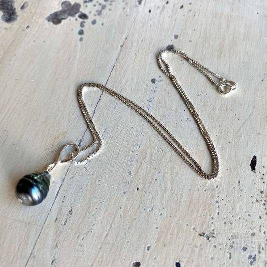 Tahitian teardrop pearl pendant box chain flat lay on tabletop, sterling silver box chain and pearl pendant