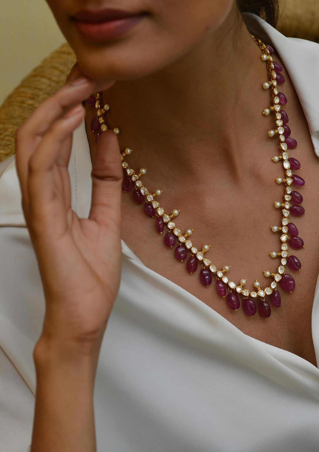 Model wearing a stunning necklace featuring ruby gems, celebrating the July birthstone ruby.