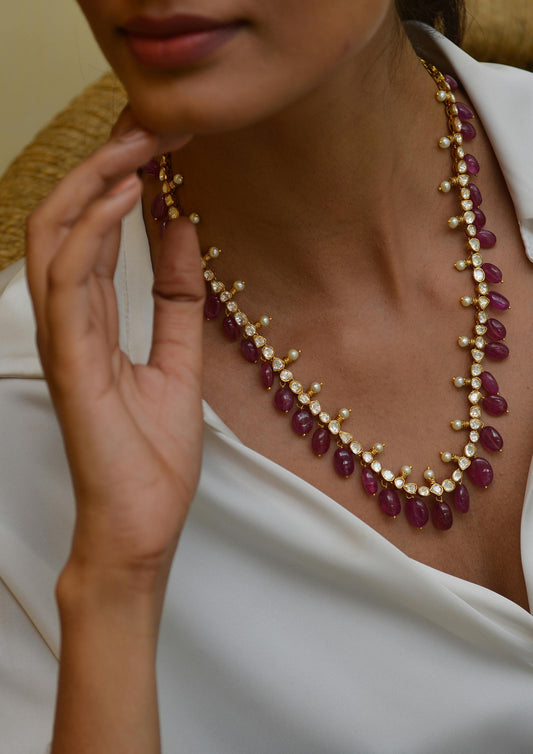 Model wearing a stunning necklace featuring ruby gems, celebrating the July birthstone ruby.