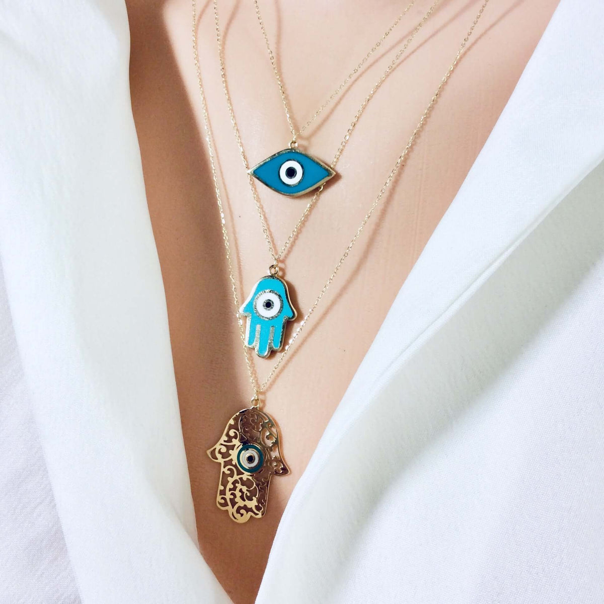 Stylish layered necklaces featuring eye and hand pendants in 18K solid gold jewelry.