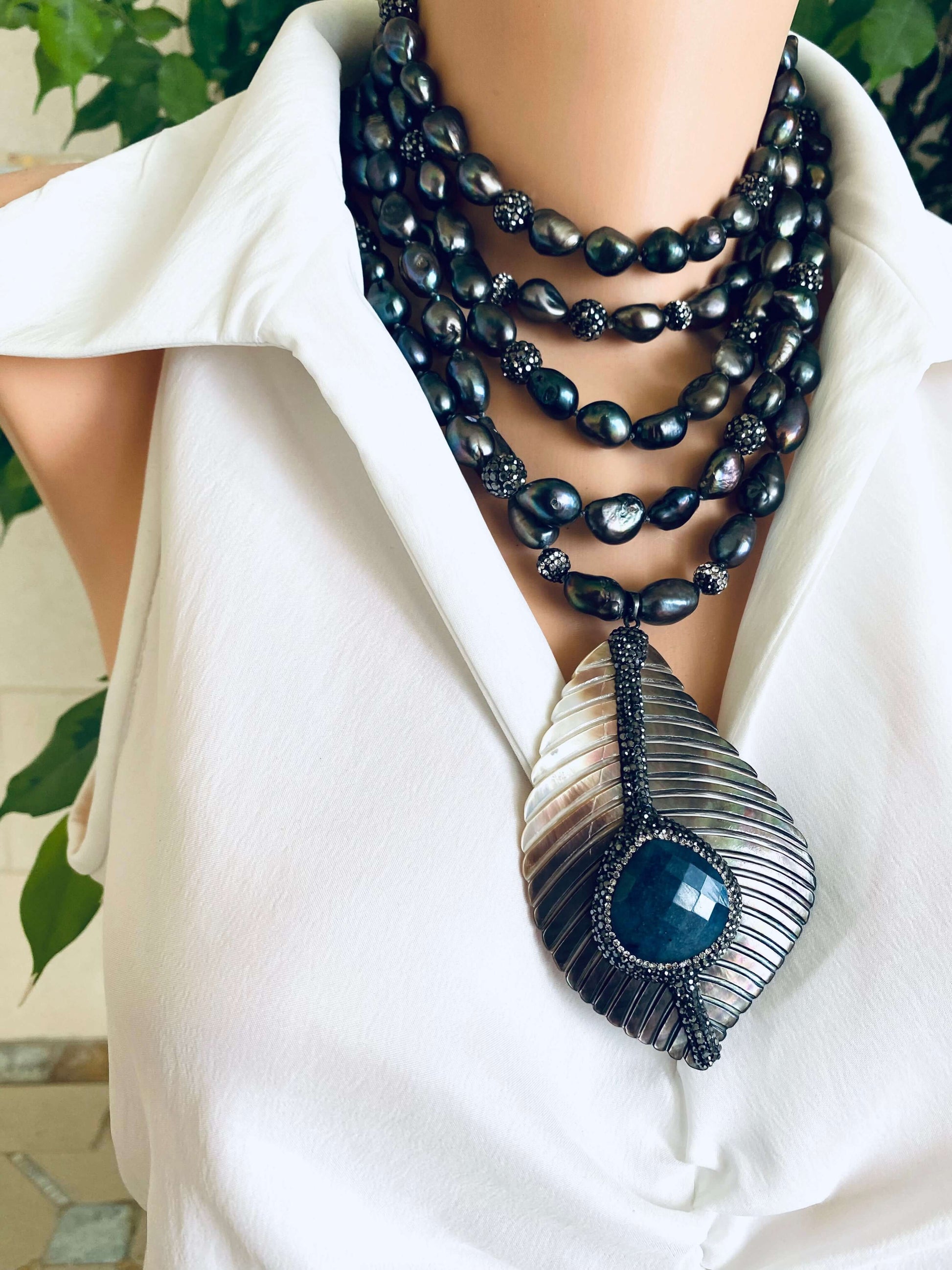 Necklace with black beads and a large blue pendant on a white background