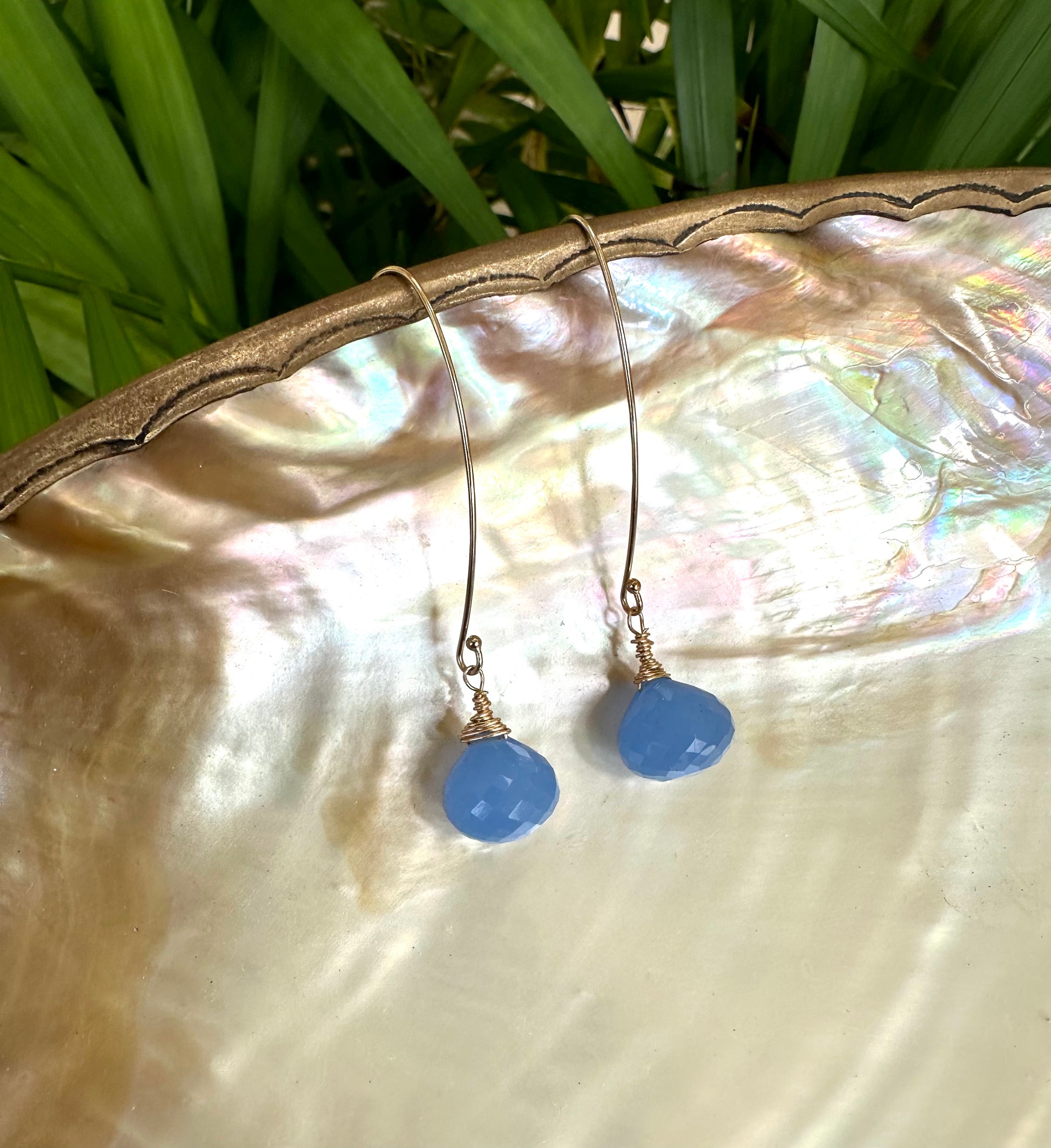 Chalcedony threader earrings with blue briolettes displayed on a decorative plate, highlighting their elegant design.