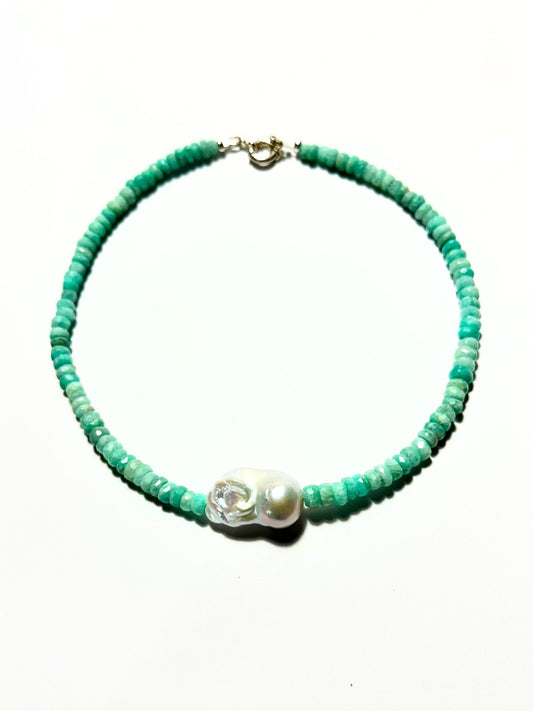 A beaded necklace featuring small turquoise-green beads, a white baroque pearl, and a silver clasp, displayed on a clean white background.
