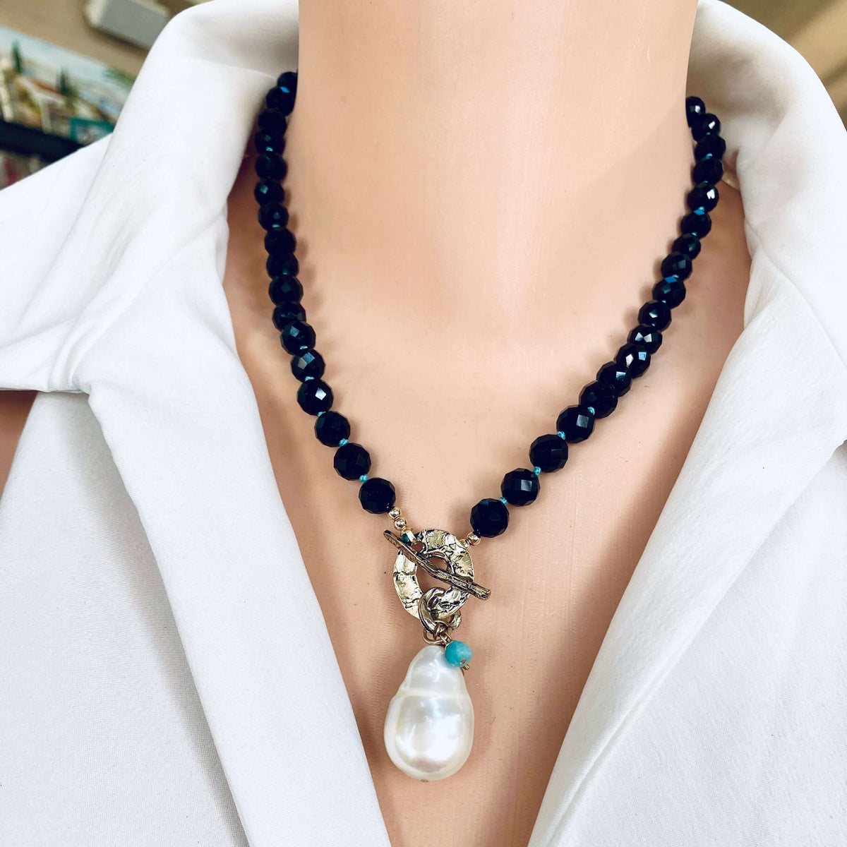 Black tourmaline baroque pearl toggle necklace worn on model showing pearl pendant and charms