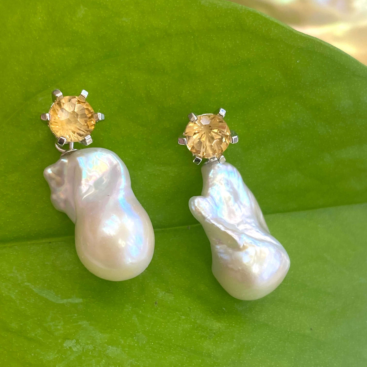 Citrine stud earrings with removable baroque pearl drops on green leaf backdrop