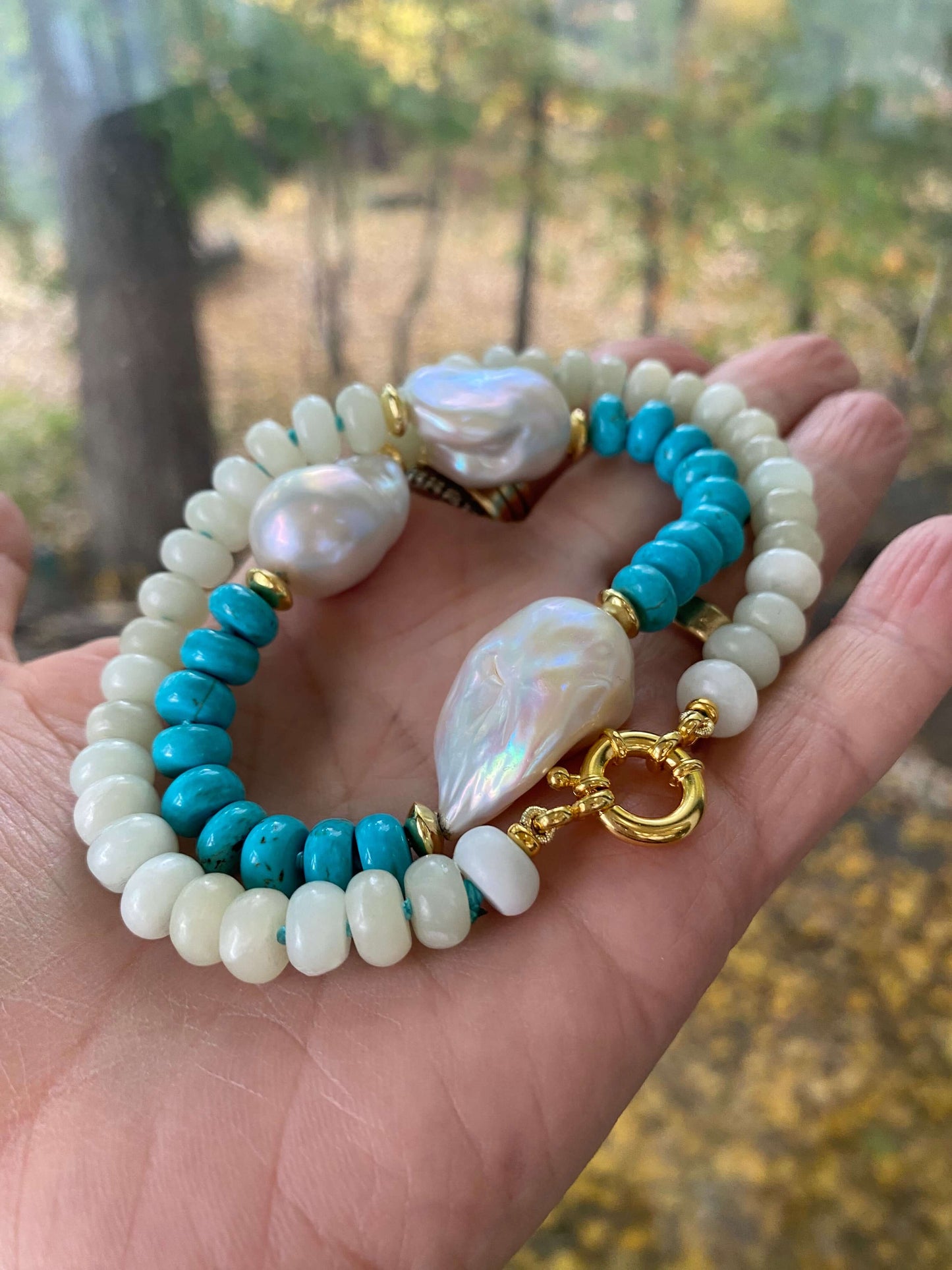 Close up of green jade and turquoise pearl necklace in hand, natural light