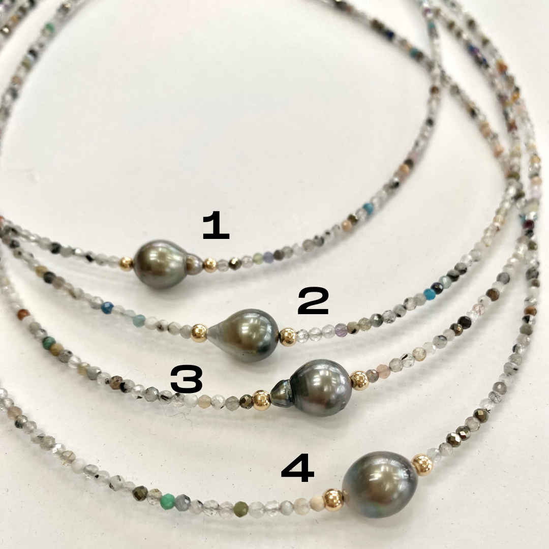 Multi stone pearl necklace color comparison with multiple gemstone tones on white cloth