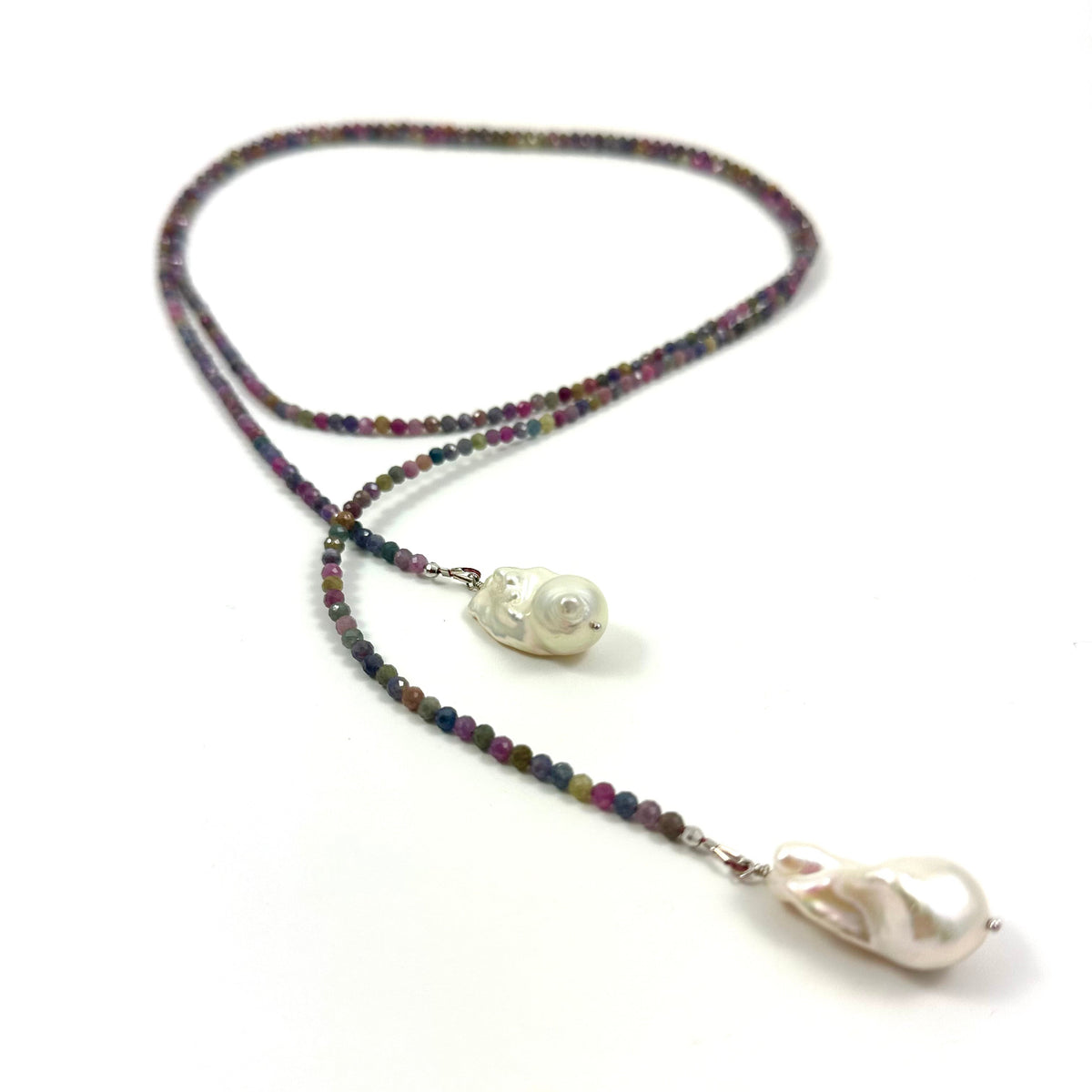 A beaded necklace with iridescent multicolor beads, featuring a carved white bead pendant and a larger teardrop-shaped white pearl pendant, displayed on a clean white background.