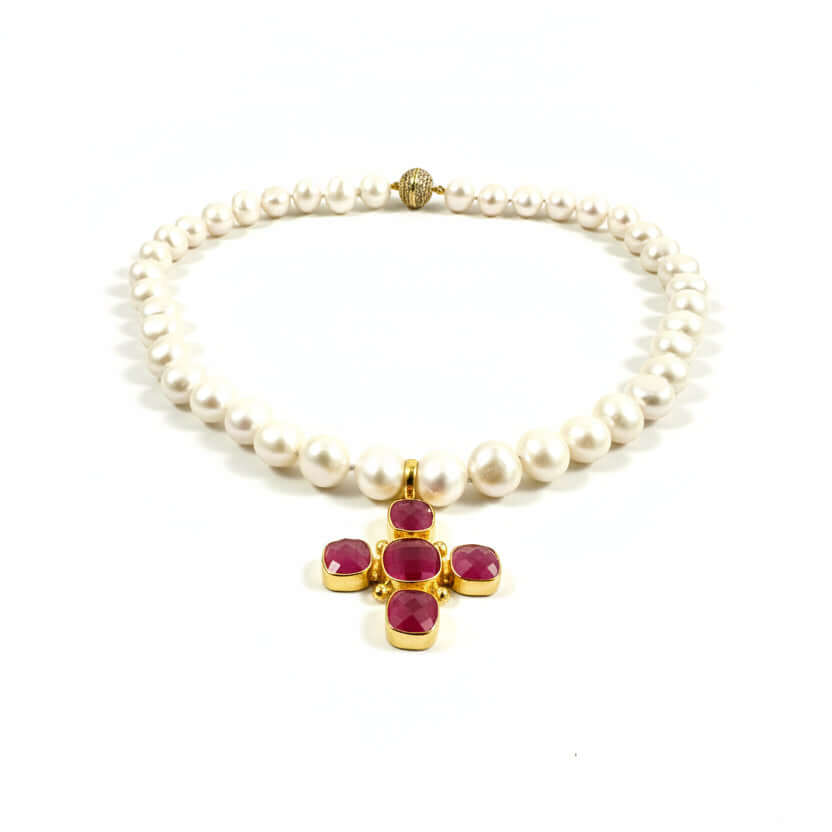 A pearl necklace with a gold cross pendant featuring four faceted magenta-pink gemstones, displayed on a clean white background.