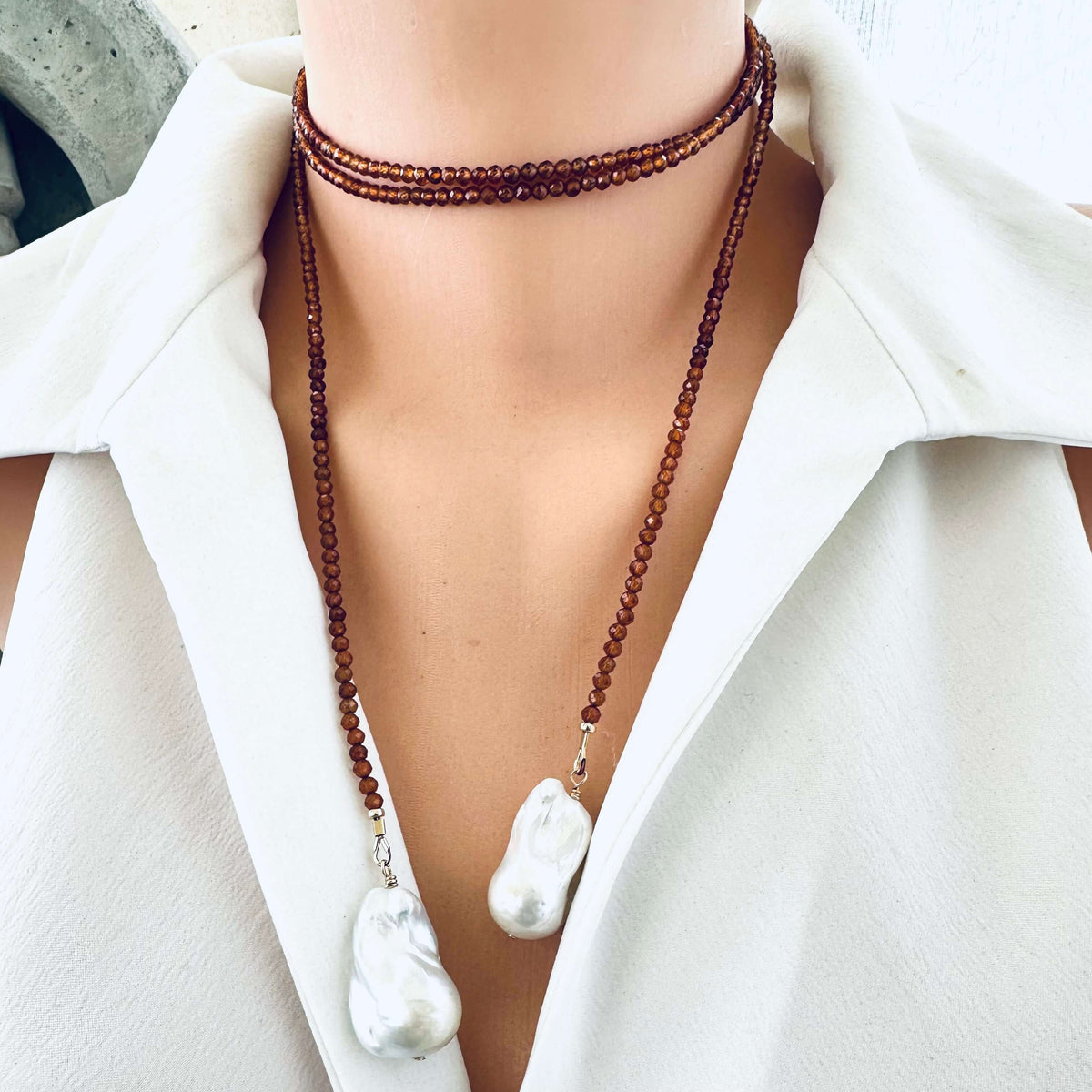 Hessonite Garnet and Baroque Pearl Lariat Necklace worn choker style on mannequin in white blouse, designed and handmade in Canada.