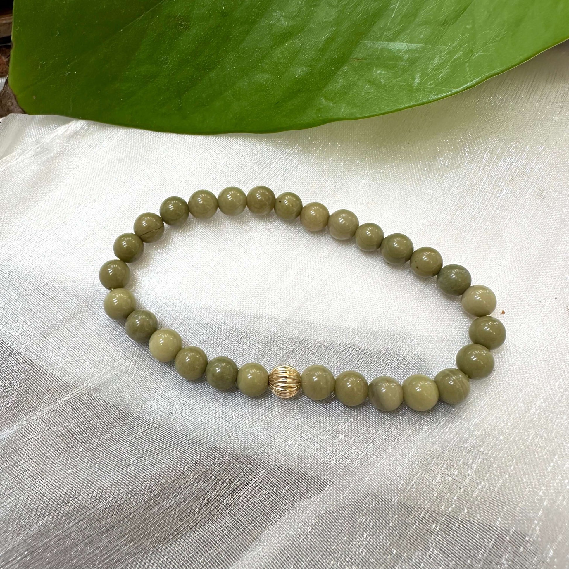 Green Olivine Jasper Bracelet on white cloth – bead and gold accent detail shot
