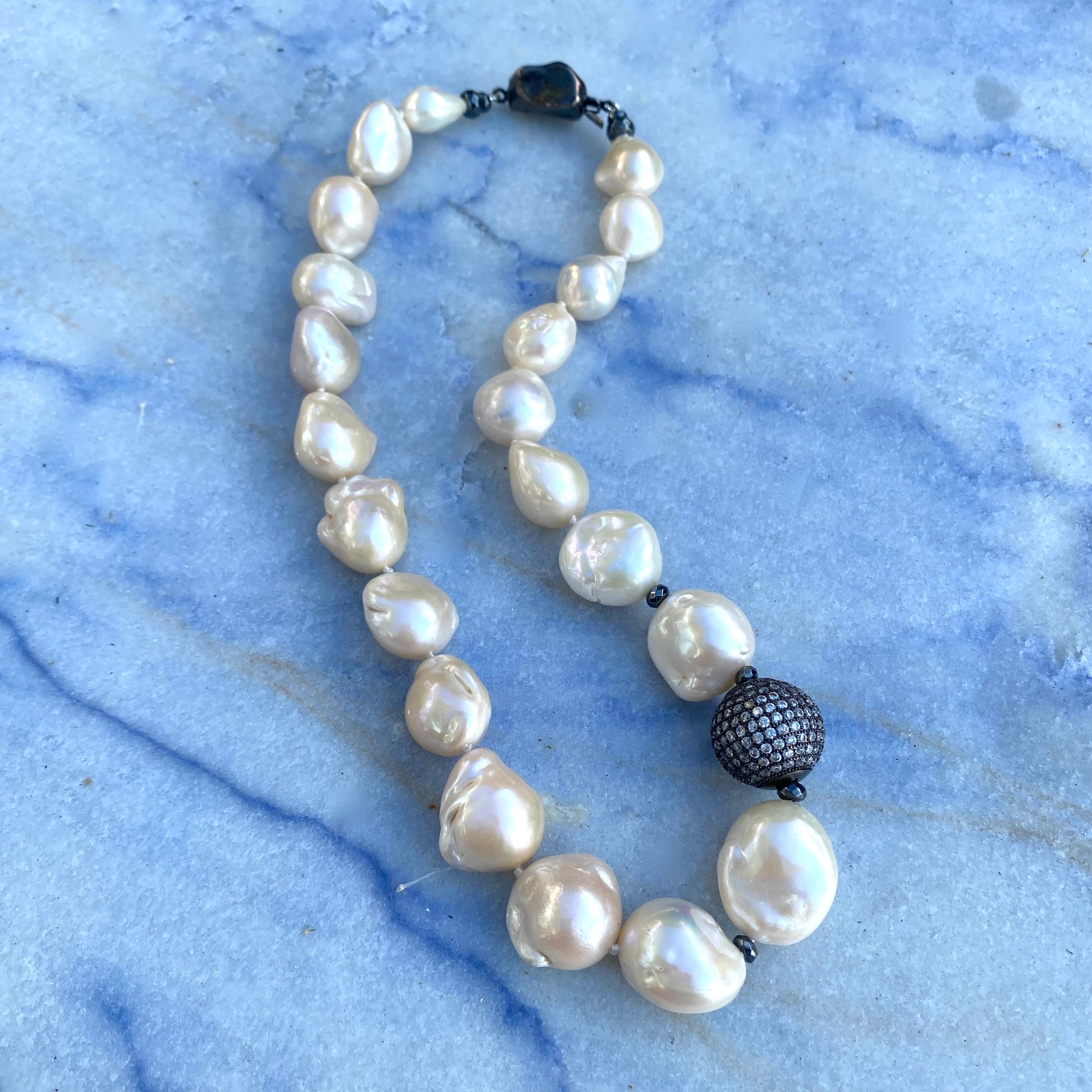 Ivory baroque pearl bridal necklace displayed flat showing hand-knotted strand and statement clasp