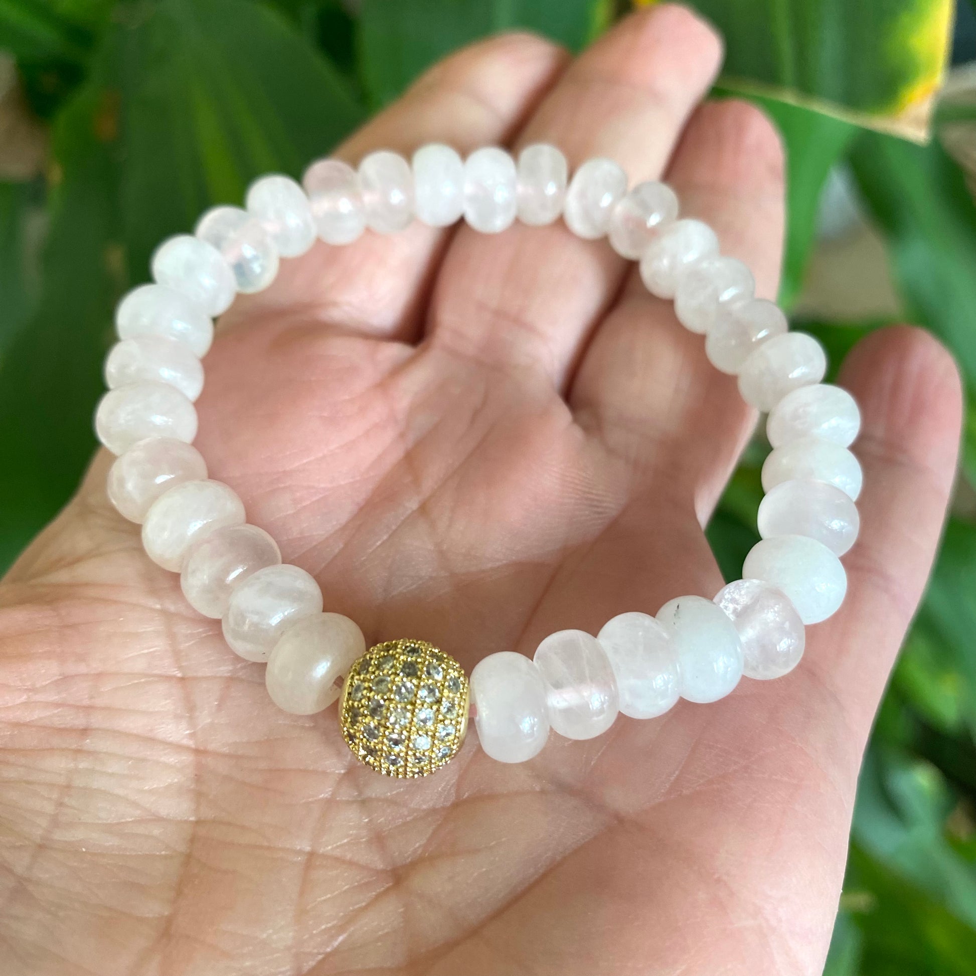 Rose quartz stretch bracelet with gold accent beads displayed on a hand, showcasing its elegant design.