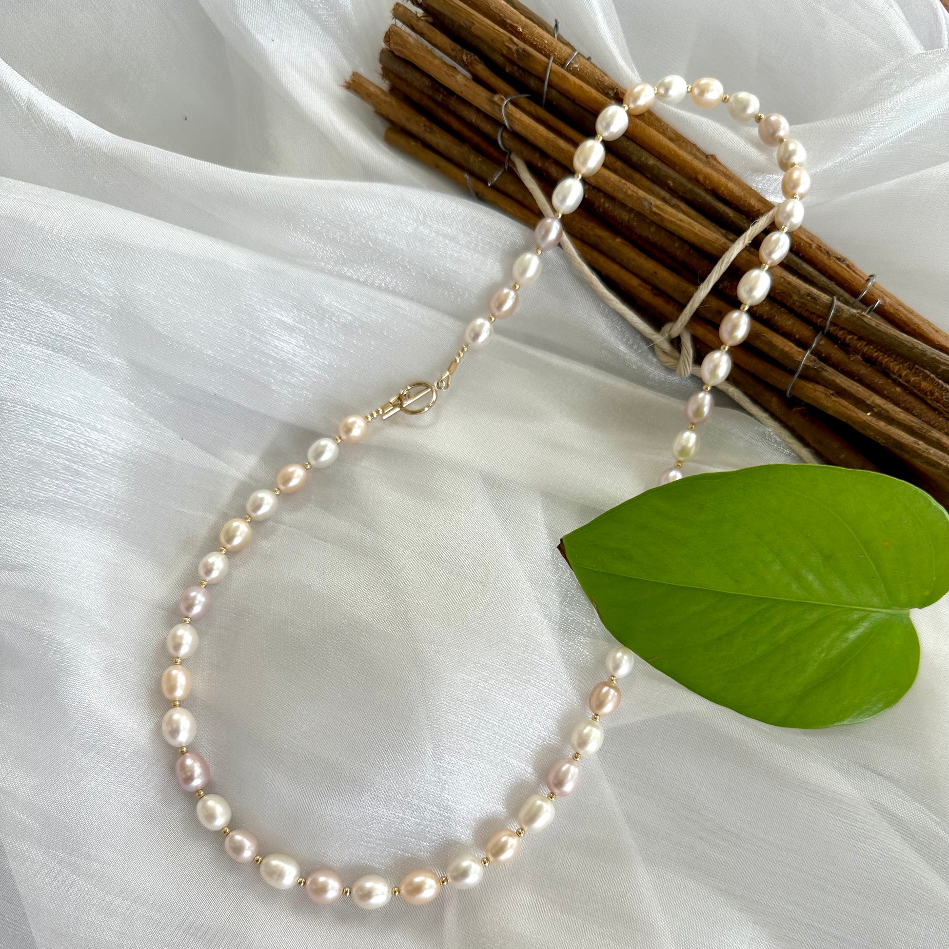 Pastel pearl necklace displayed on white cloth background