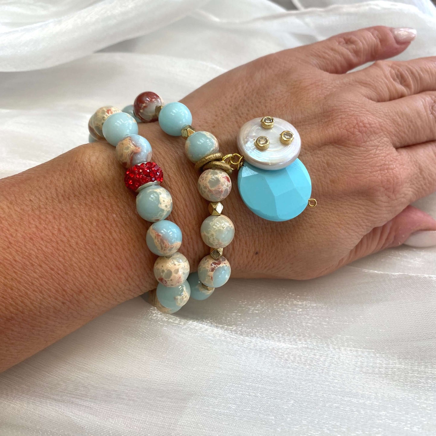 Pale blue deep red stretchy bracelet stack worn on wrist showing layered gemstone textures