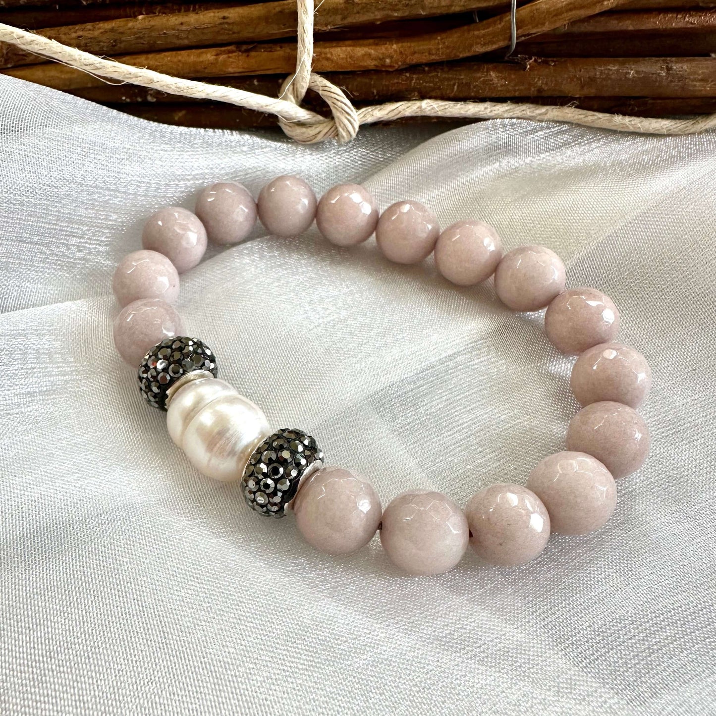 Pink jade pearl bracelet displayed on white cloth background