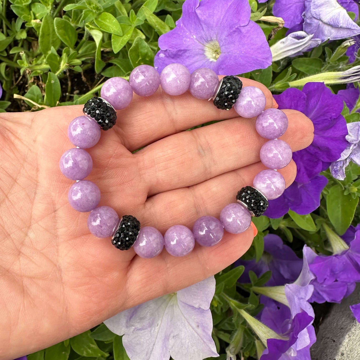 Lavender jade bracelet without pearl held in hand near purple flowers