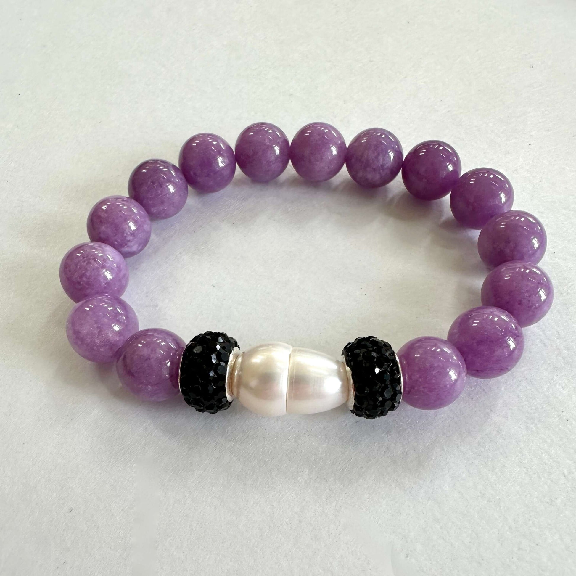 Lavender jade bracelet with one pearl displayed on white cloth
