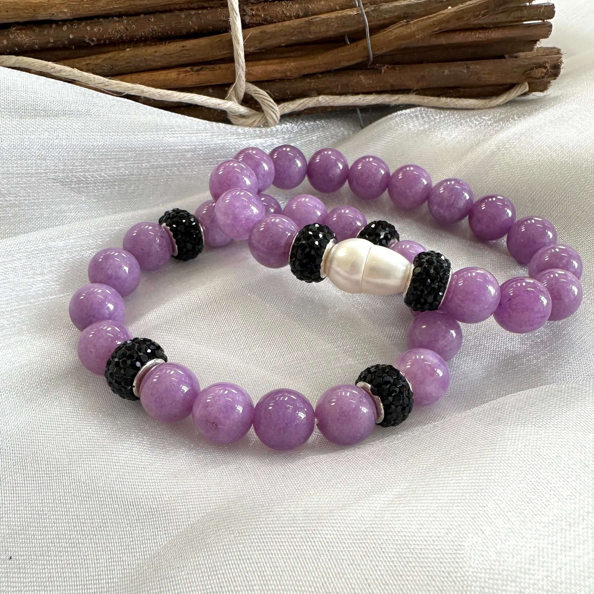 Lavender jade bracelets with and without pearl side by side on white cloth