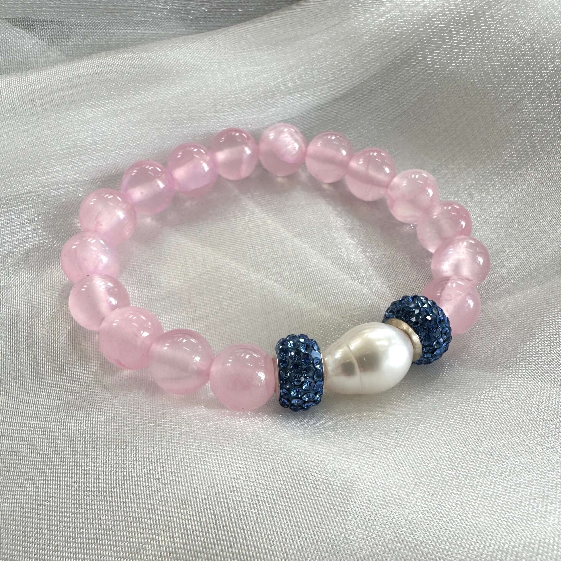 Pink jade bracelet featuring 10mm jade beads, freshwater pearl, and rhinestone accents on a soft fabric background.
