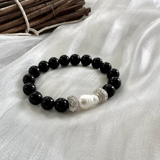 Black onyx bracelet with pearl displayed on white cloth