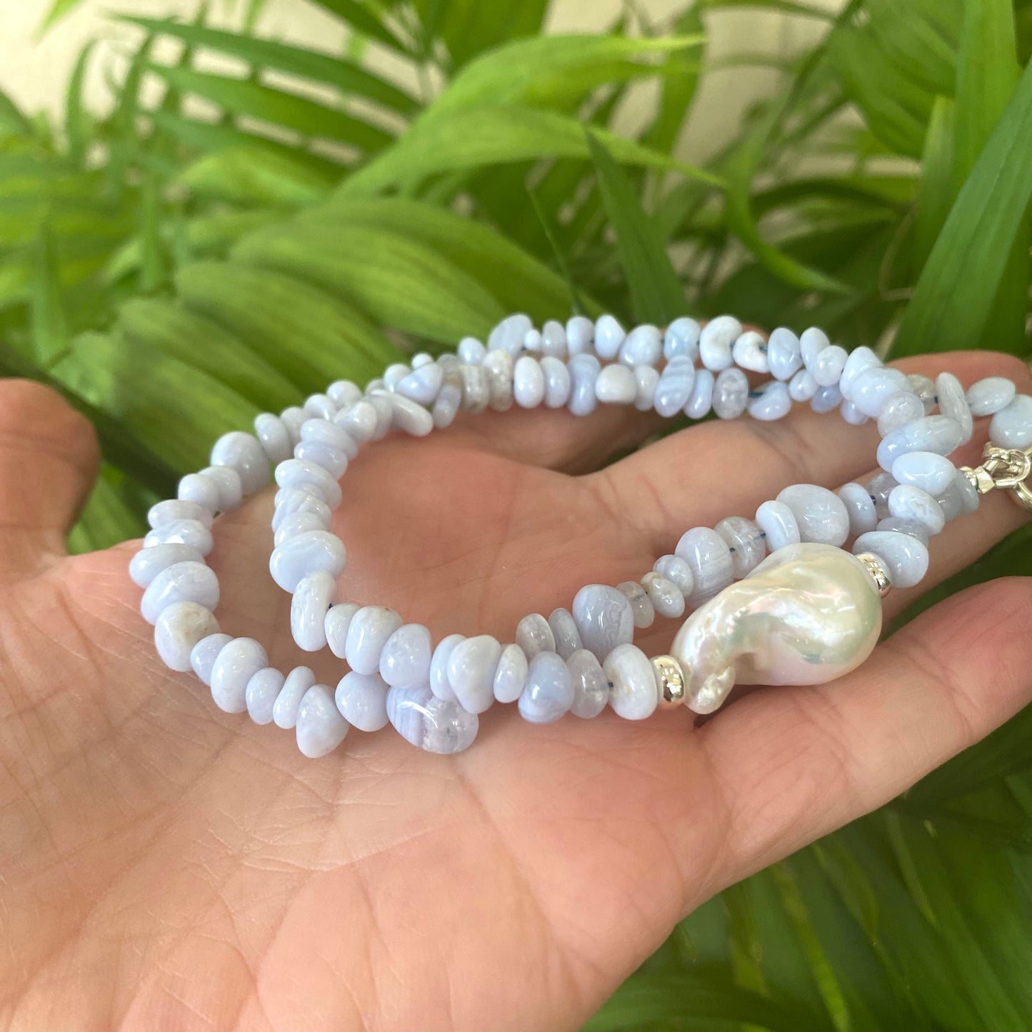 Blue lace agate pearl necklace held in hand