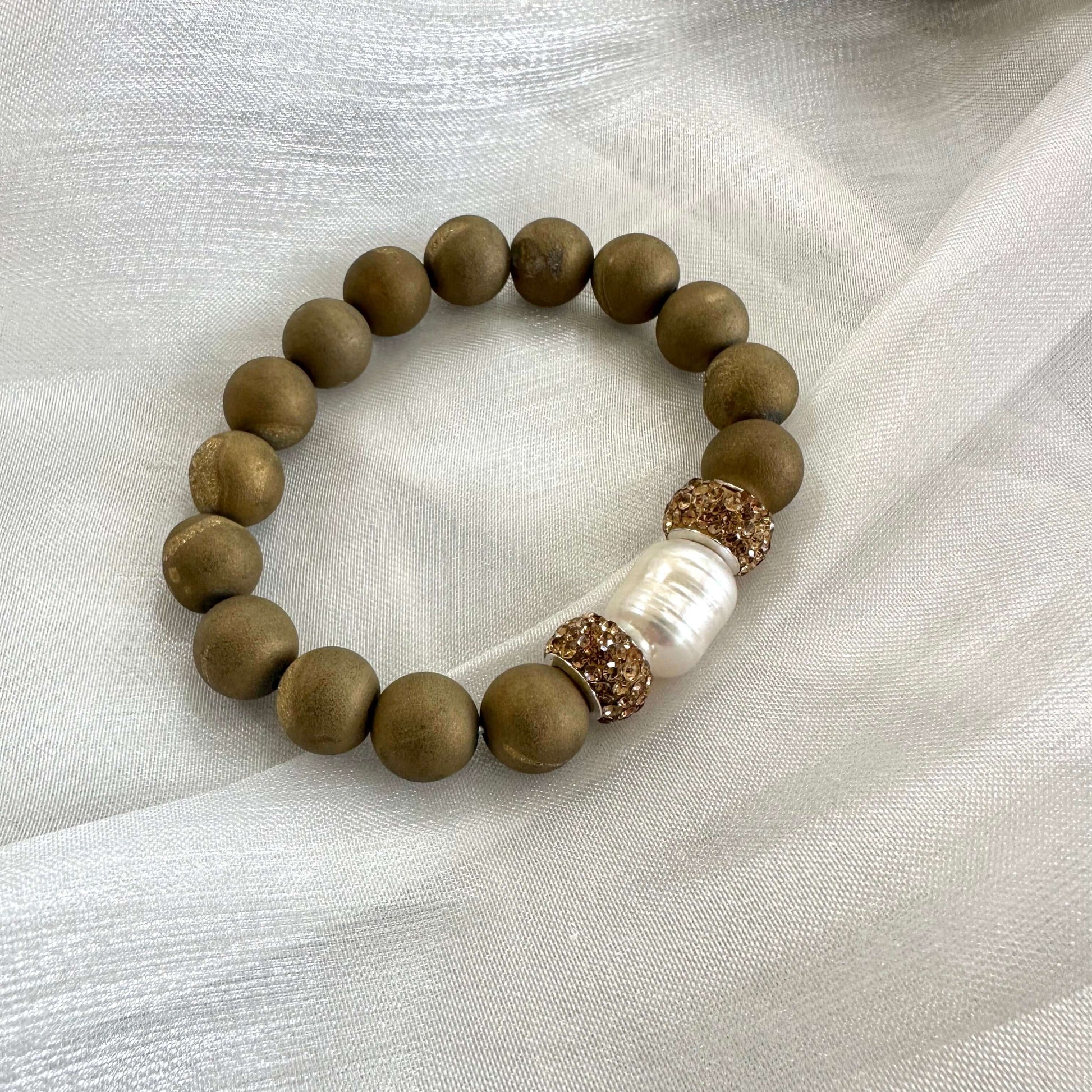 Gold druzy agate bracelet with pearl displayed on white cloth