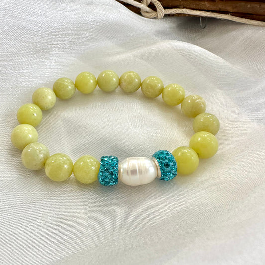Olive green jade bracelet with one pearl displayed on white cloth