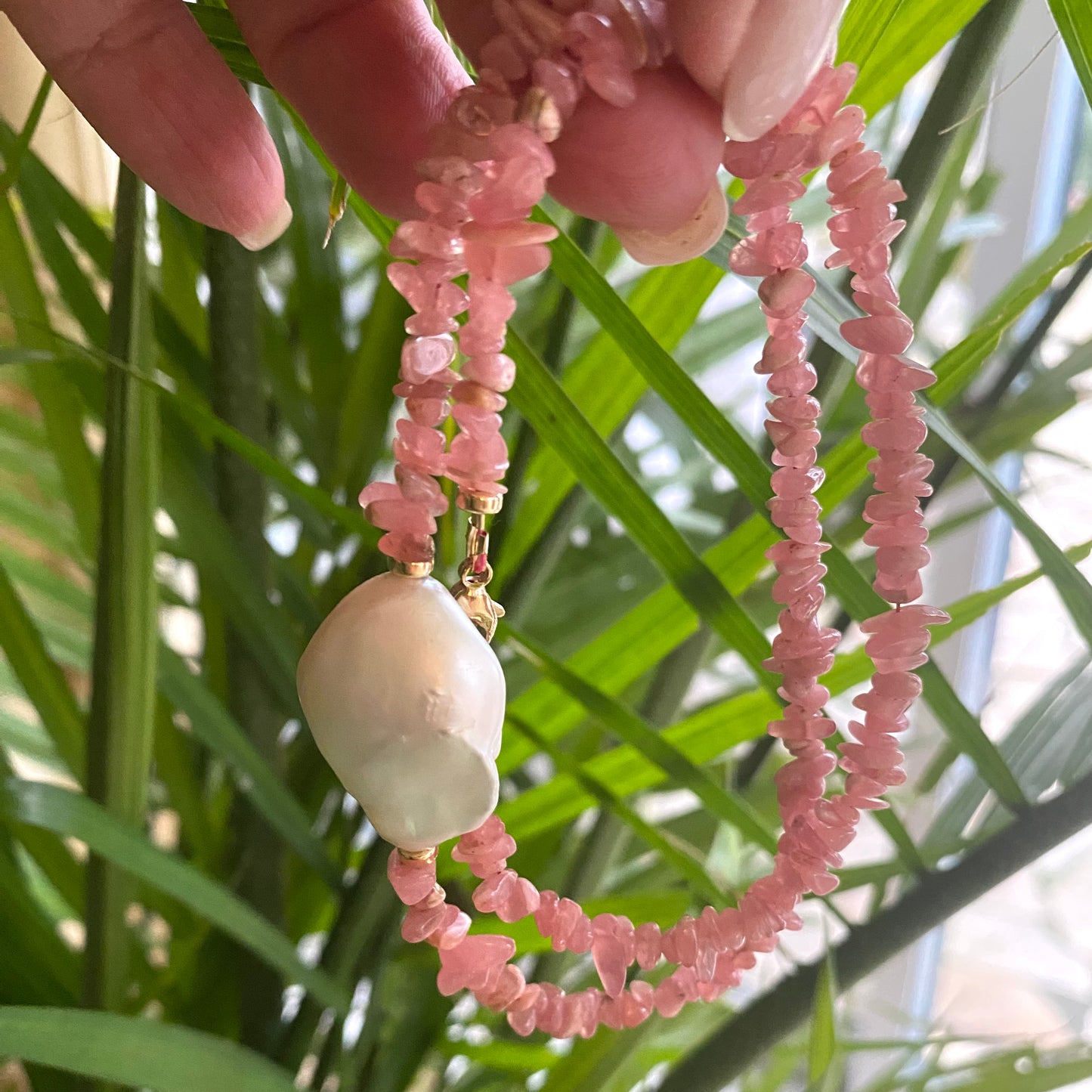 Rhodochrosite pearl necklace held in hand