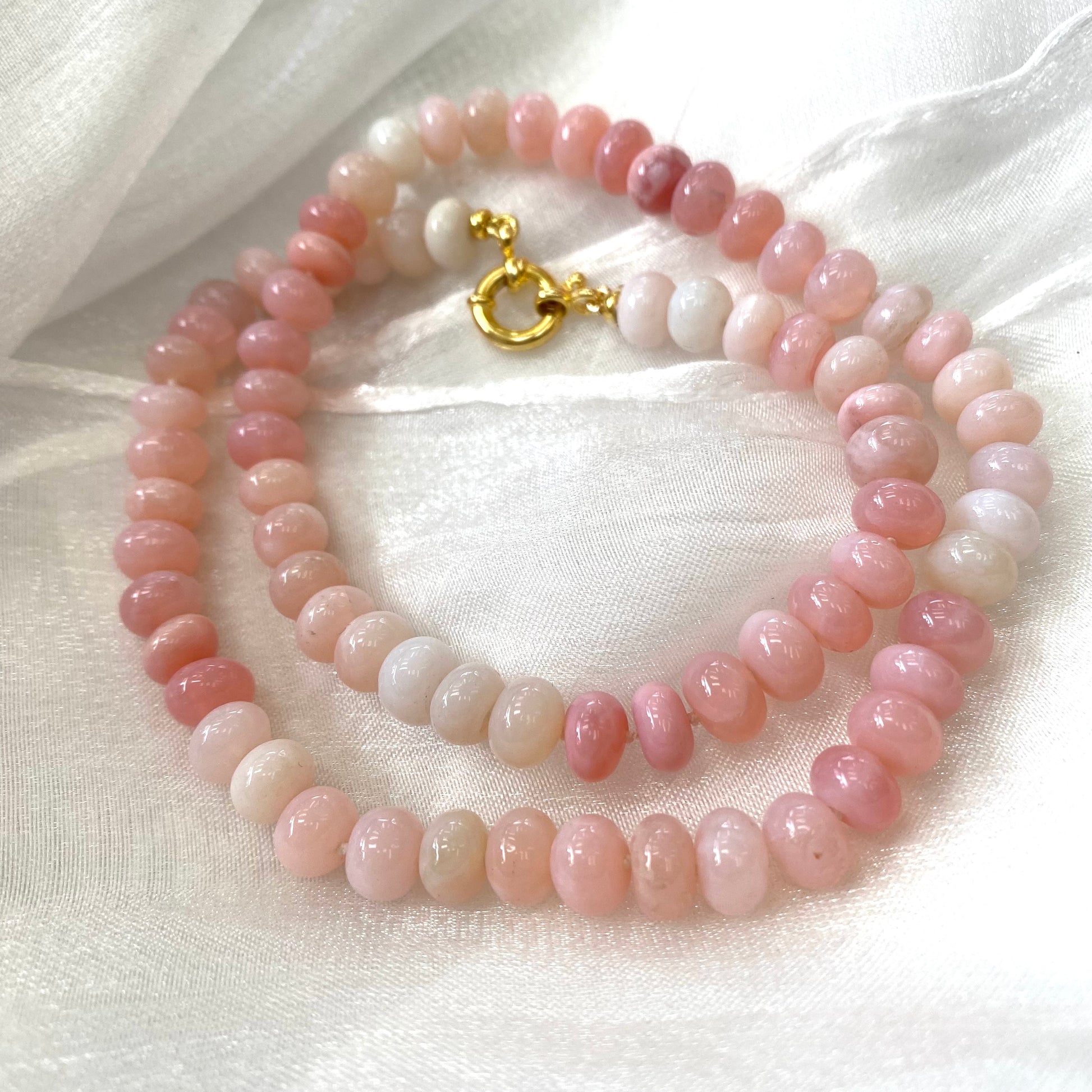 Pink opal beaded necklace displayed on white cloth