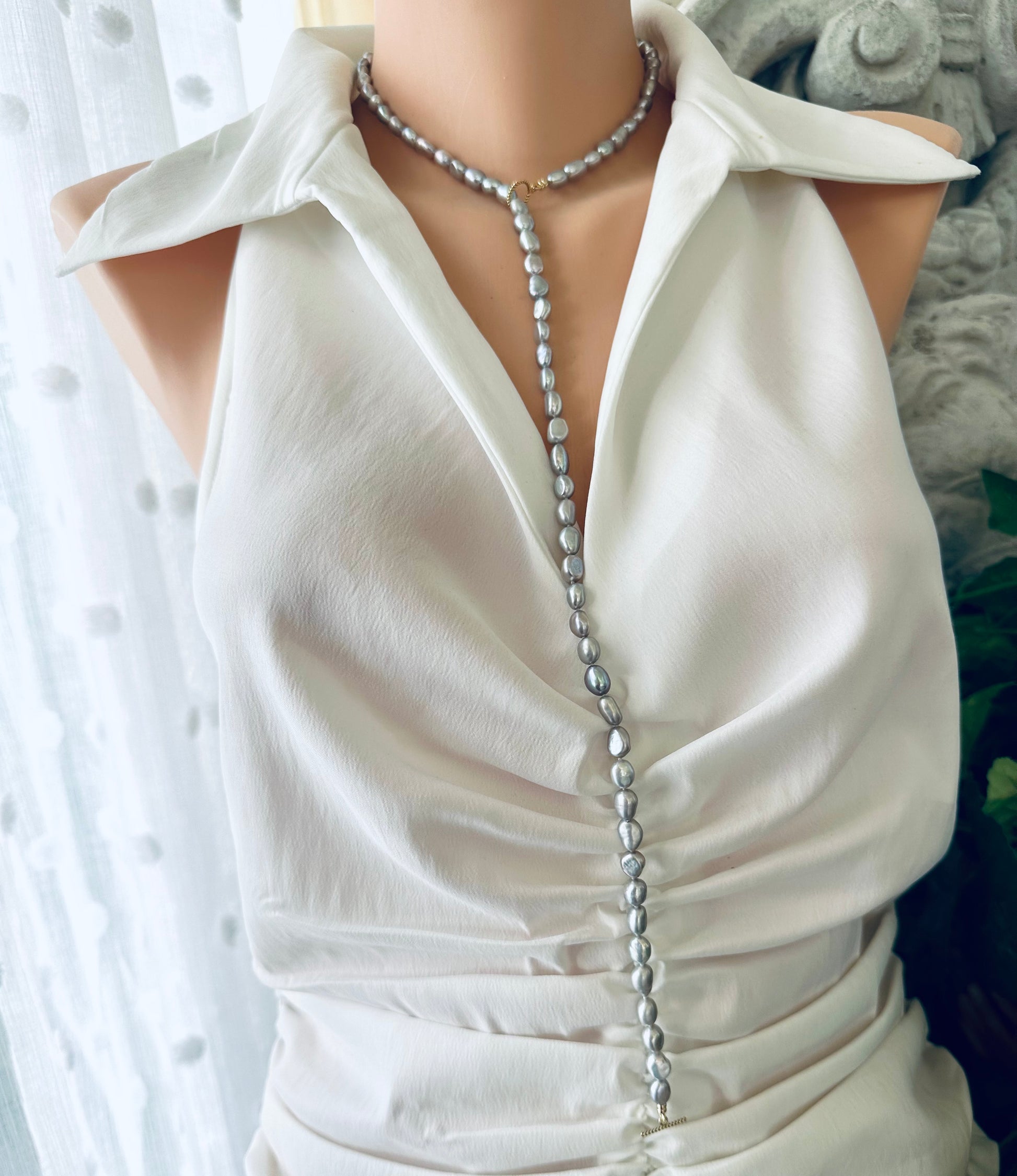 Grey nugget pearl necklace displayed elegantly on a mannequin wearing a white blouse.