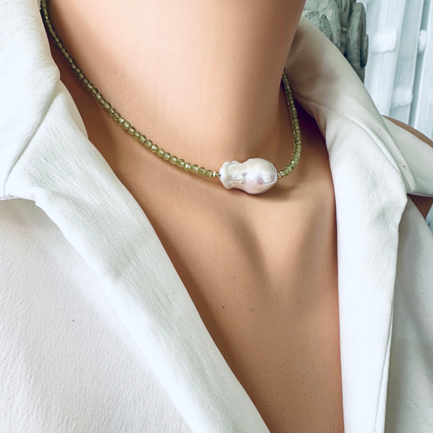 Side view of peridot and baroque pearl necklace displayed on mannequin