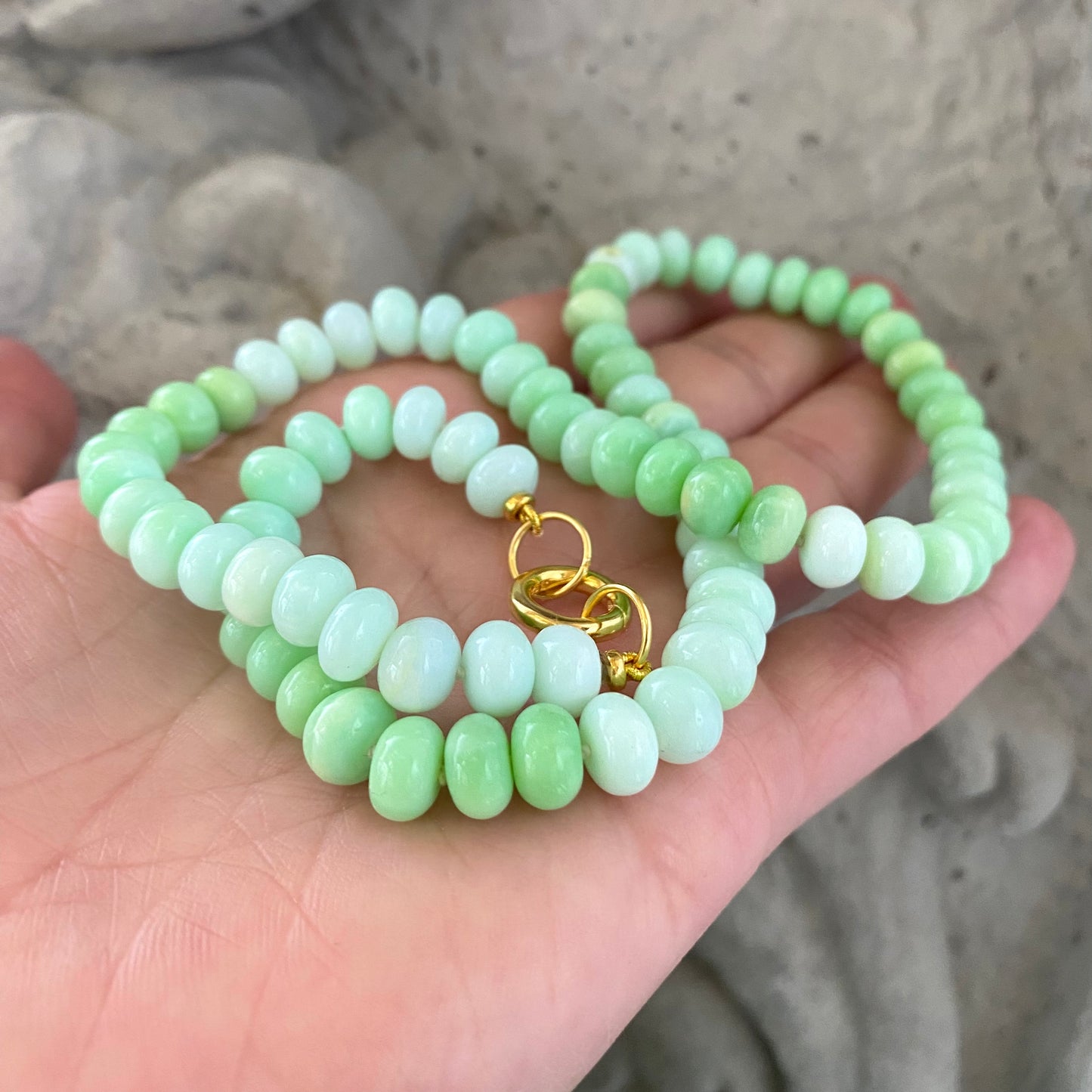 Green opal beaded necklace close-up against stone statue