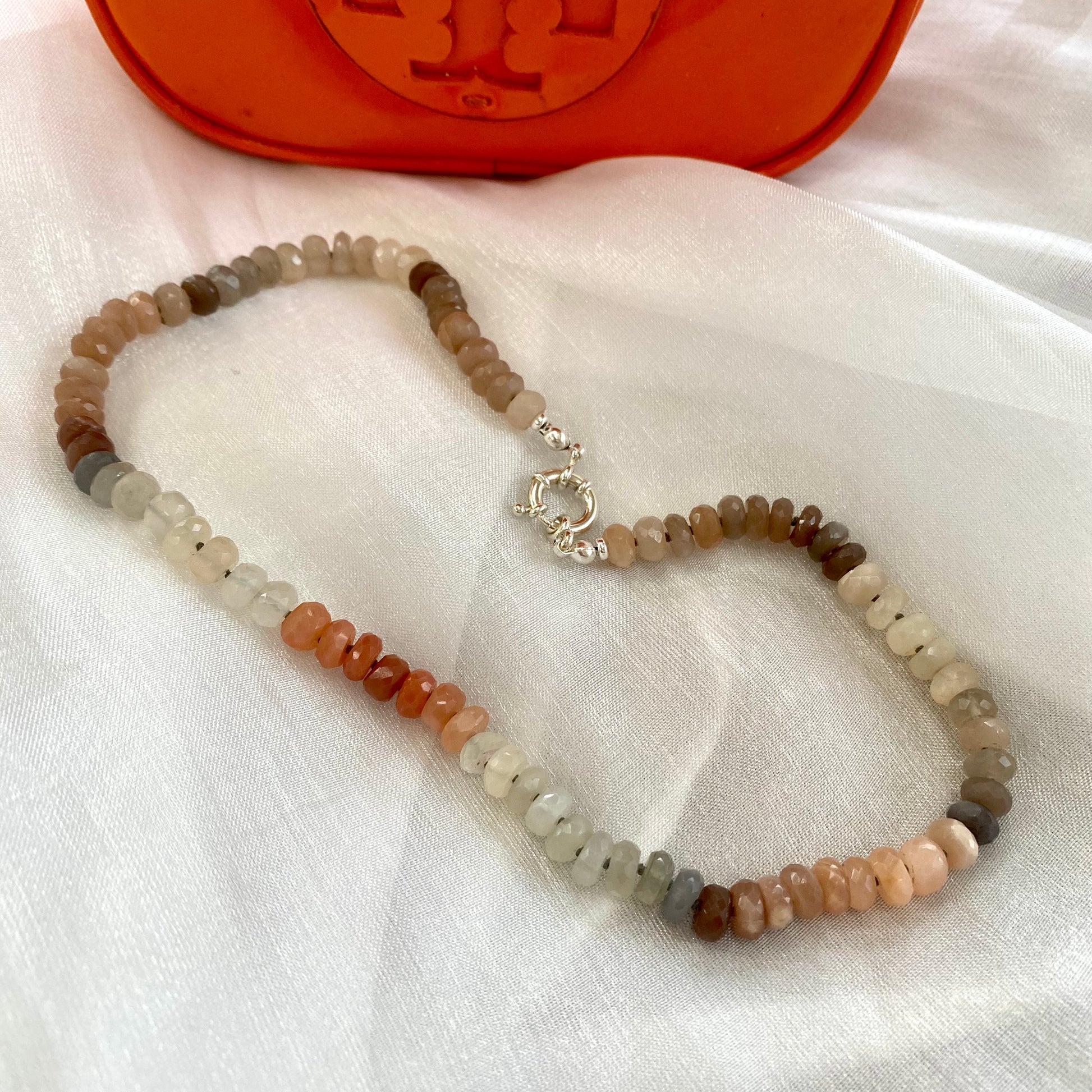 Moonstone candy necklace with sunstone beads, showcasing a mix of iridescent gems on a soft fabric background.