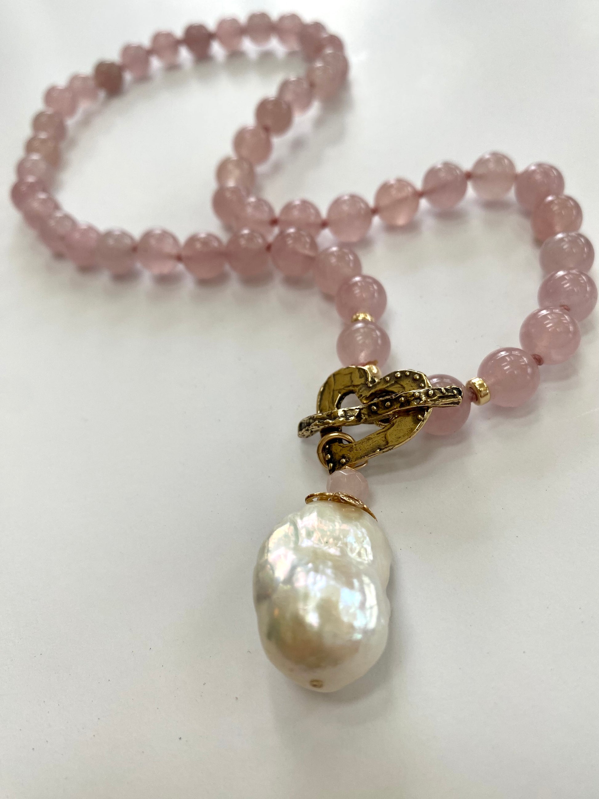 Rose quartz pearl necklace displayed on white cloth