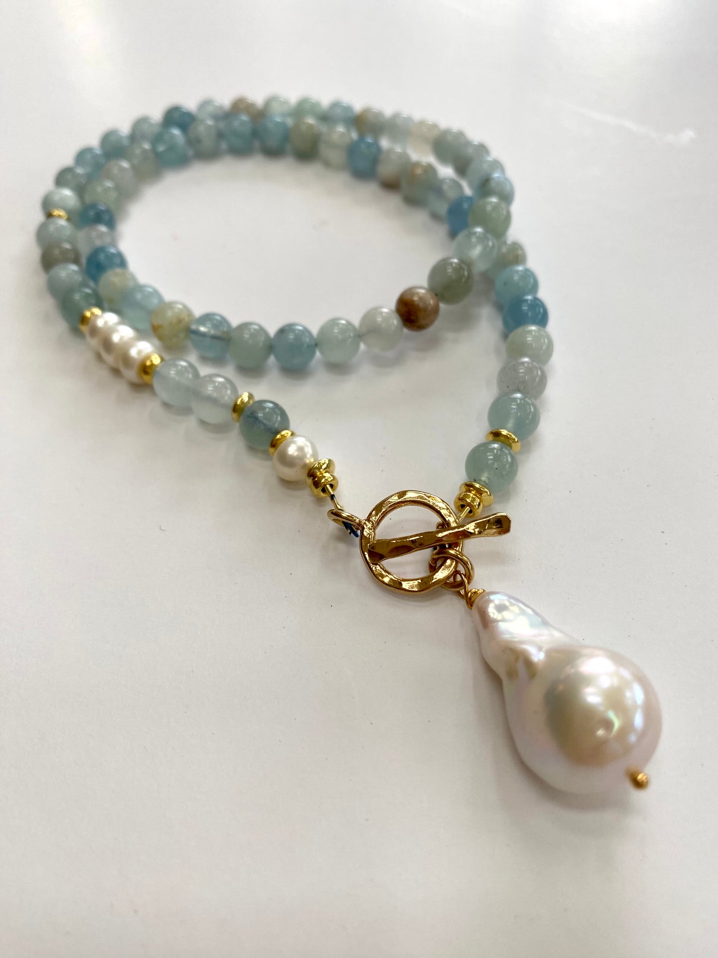 Aquamarine pearl necklace displayed on white cloth