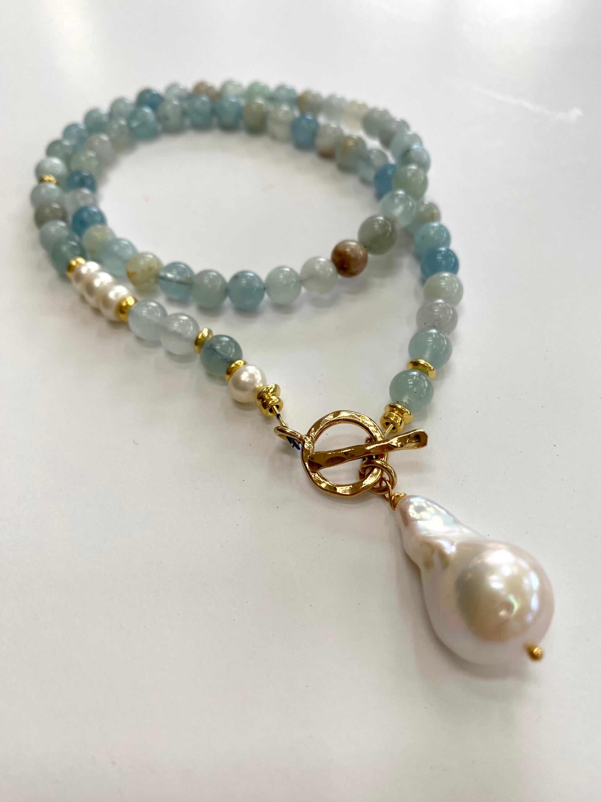 Aquamarine pearl necklace displayed on white cloth