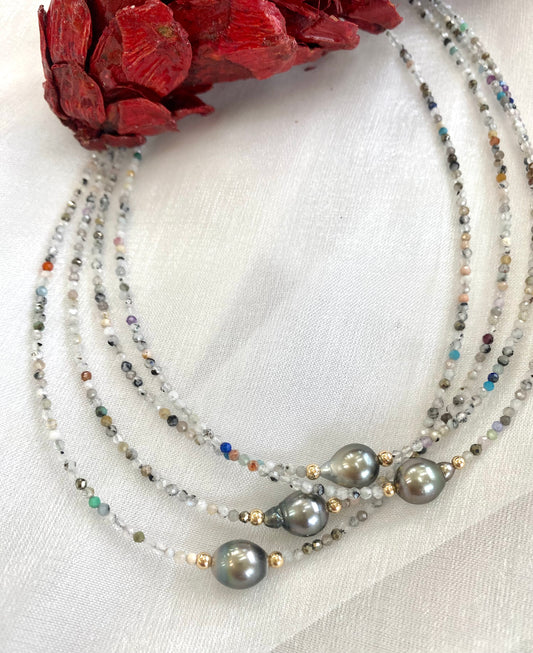 Multi stone pearl necklace displayed in different color variations on white cloth
