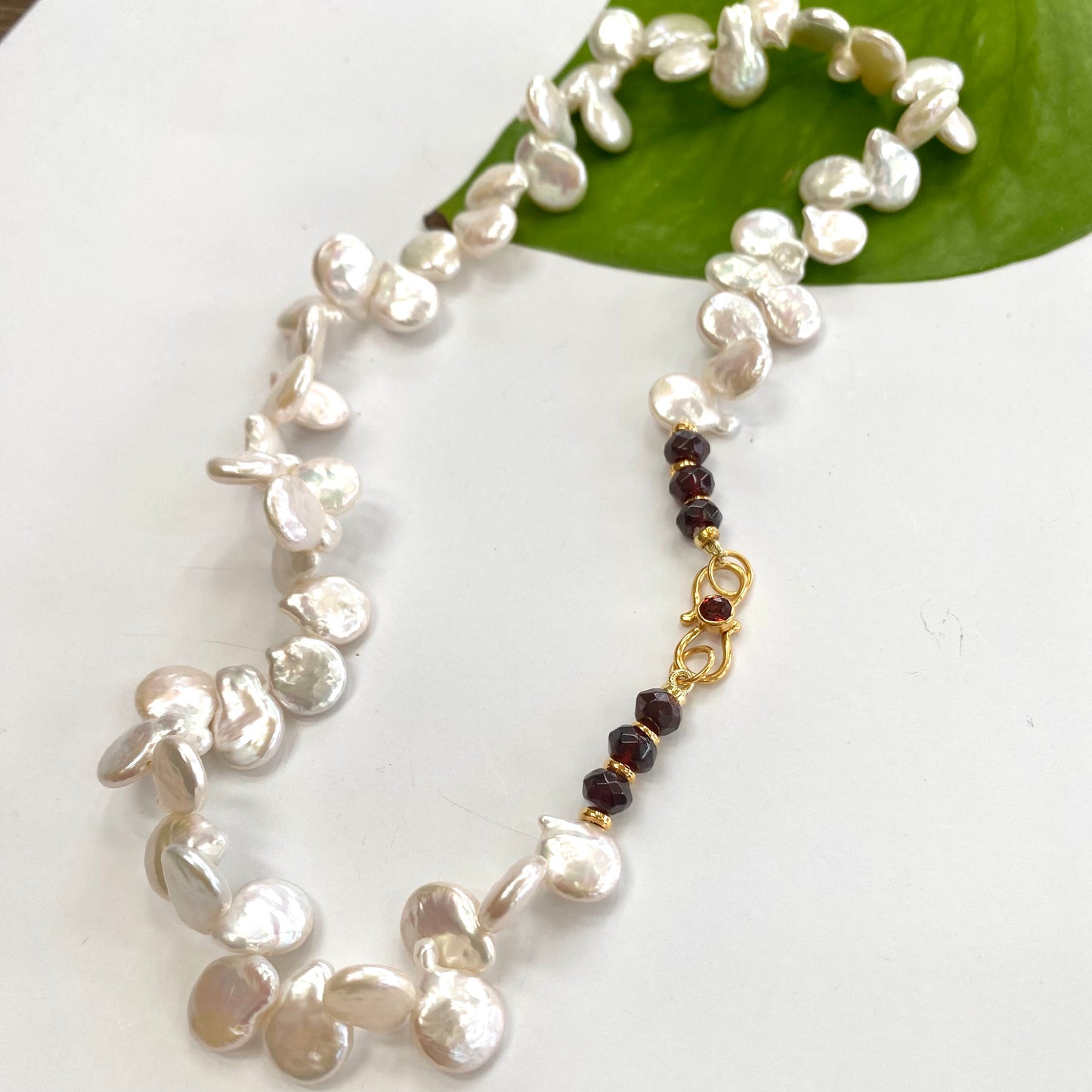 Keshi pearl necklace featuring garnet accents, showcasing unique coin-petal shaped freshwater pearls.