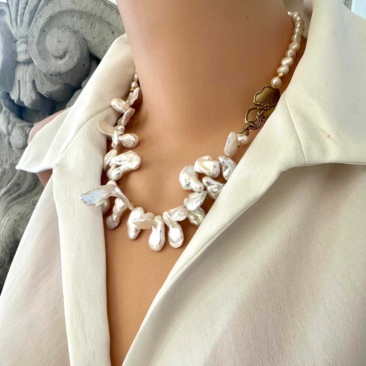 White petal pearl necklace worn by mannequin side view showing golden vine leaf toggle clasp