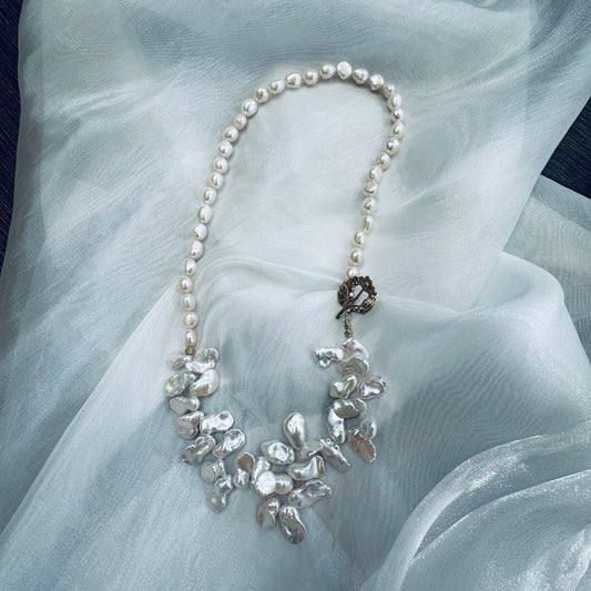 White keshi pearl necklace displayed on white cloth table showing nugget and petal pearls