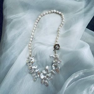 Add a touch of organic elegance to your look with this stunning 25" white Keshi pearls necklace, featuring a unique asymmetrical design that showcases both petal-shaped and nugget pearls. 
At the side, a beautiful golden palm leaf toggle clasp adds a tropical flair