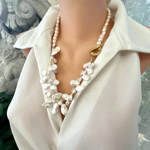 Add a touch of organic elegance to your look with this stunning 25" white Keshi pearls necklace, featuring a unique asymmetrical design that showcases both petal-shaped and nugget pearls. 
At the side, a beautiful golden palm leaf toggle clasp adds a tropical flair