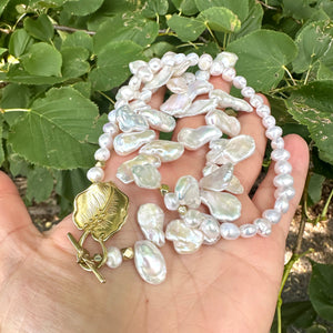 Stunning 19" white Keshi pearls necklace, featuring a unique asymmetrical design that showcases both petal-shaped and nugget pearls with a beautiful golden vine leaf toggle clasp making this necklace not only easy to wear but a striking focal point.