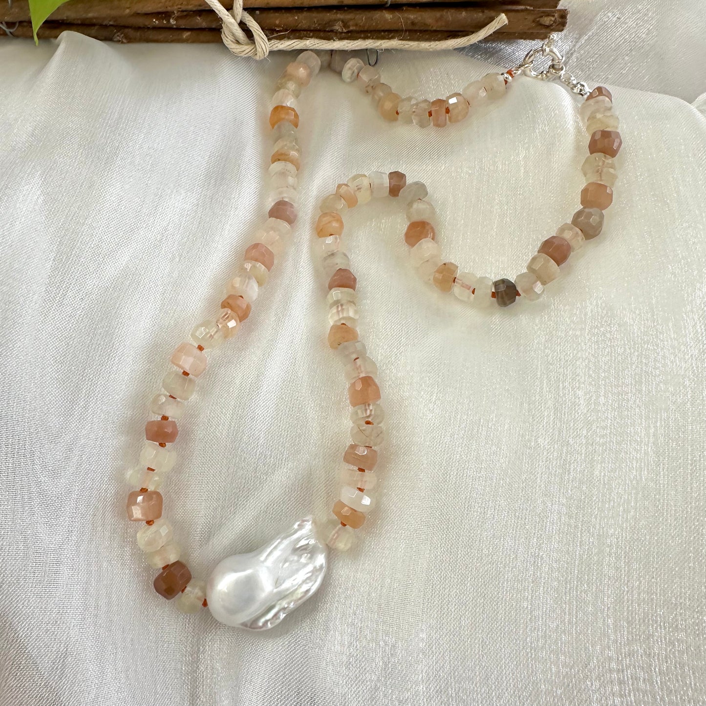 Mixed moonstone and baroque pearl necklace on white cloth background showing silver clasp